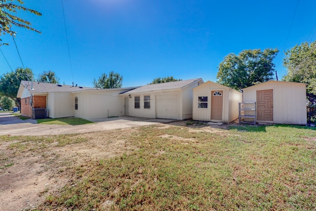 back of property with an outbuilding, a yard, an attached garage, a storage shed, and driveway