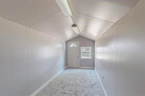 hallway with light colored carpet and vaulted ceiling