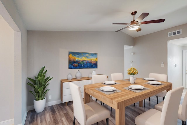 dining area featuring baseboards, visible vents, a ceiling fan, wood finished floors, and vaulted ceiling