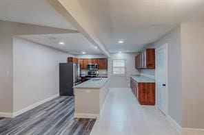 kitchen featuring hardwood / wood-style flooring, beam ceiling, kitchen peninsula, and stainless steel appliances