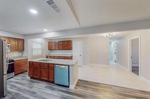 kitchen with appliances with stainless steel finishes, sink, an island with sink, and wood-type flooring