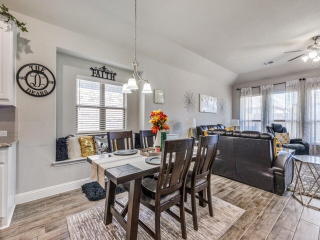 dining room featuring vaulted ceiling, hardwood / wood-style floors, and ceiling fan with notable chandelier