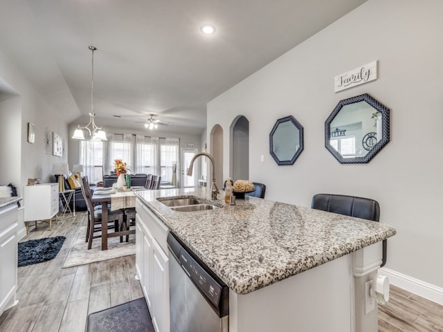 kitchen featuring sink, stainless steel dishwasher, decorative light fixtures, white cabinets, and light wood-type flooring