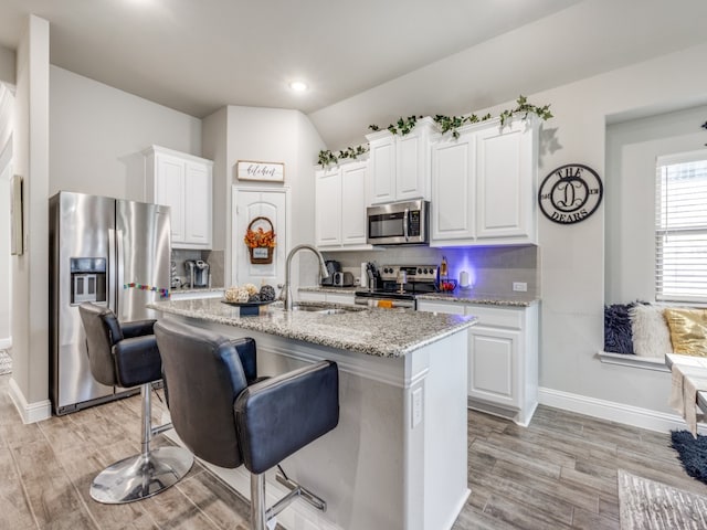 kitchen featuring white cabinets, light wood-type flooring, an island with sink, and appliances with stainless steel finishes