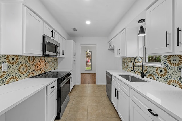 kitchen featuring hanging light fixtures, white cabinets, stainless steel appliances, and sink