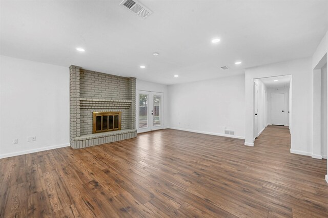 unfurnished living room with a fireplace, french doors, and dark wood-type flooring