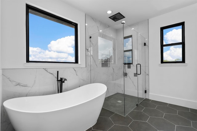 bathroom featuring tile patterned flooring, independent shower and bath, tile walls, and a healthy amount of sunlight