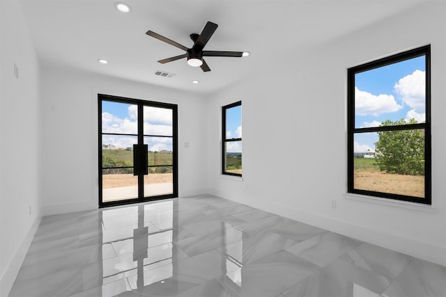 spare room with ceiling fan and plenty of natural light