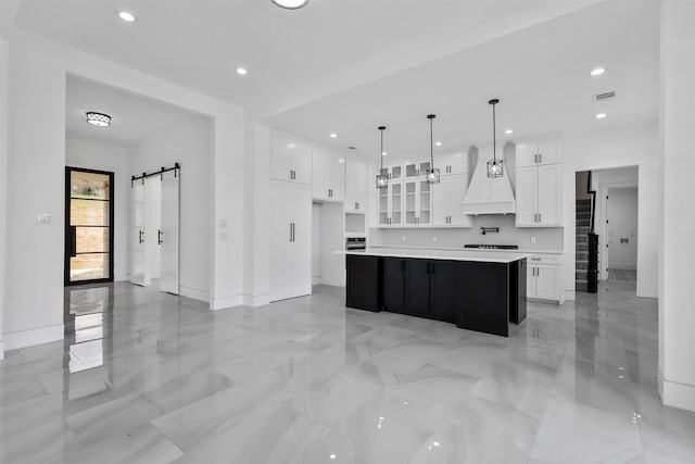 kitchen featuring decorative light fixtures, white cabinetry, a kitchen island, and custom exhaust hood