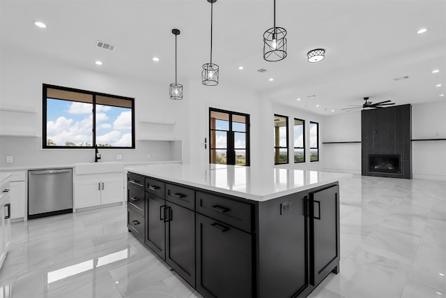 kitchen with pendant lighting, stainless steel dishwasher, ceiling fan, a kitchen island, and white cabinetry