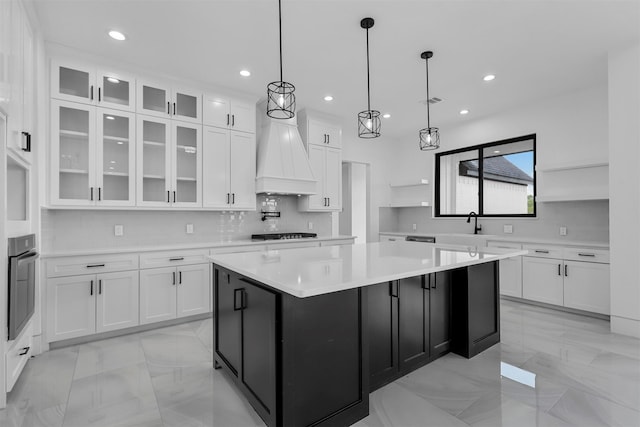 kitchen with white cabinets, oven, custom range hood, and a large island