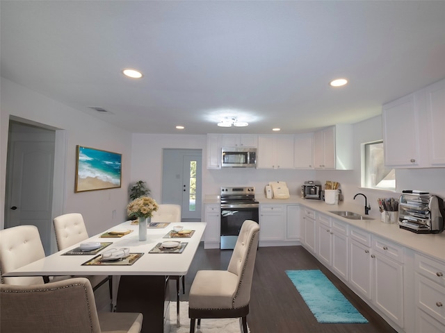 kitchen with dark hardwood / wood-style flooring, white cabinetry, sink, and stainless steel appliances