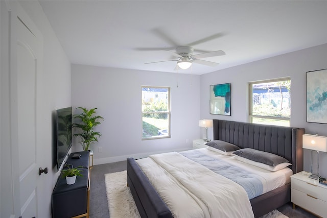 bedroom featuring dark colored carpet, ceiling fan, and multiple windows