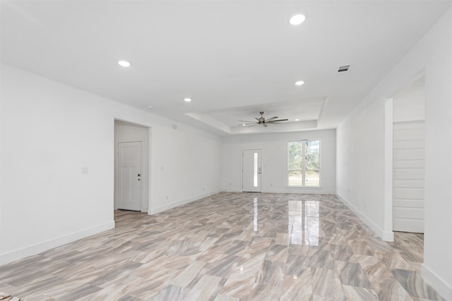 spare room with a tray ceiling and ceiling fan