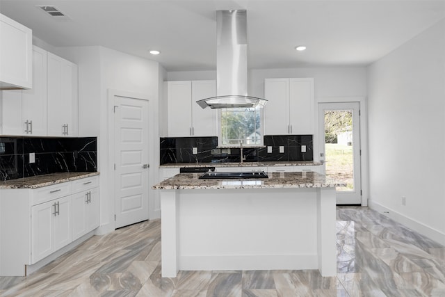 kitchen featuring white cabinetry, decorative backsplash, island range hood, and light stone countertops