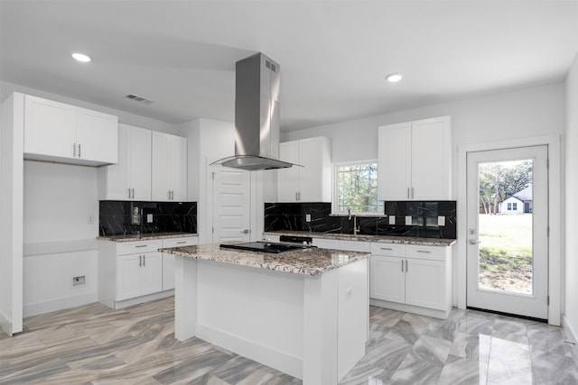 kitchen with backsplash, island range hood, a healthy amount of sunlight, white cabinets, and a kitchen island