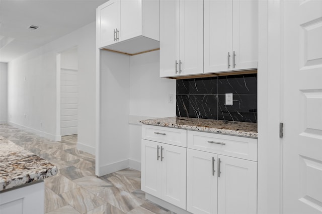 kitchen featuring decorative backsplash, white cabinetry, and light stone counters