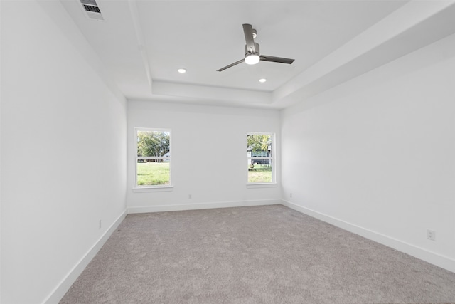 unfurnished room featuring light colored carpet, a raised ceiling, and ceiling fan