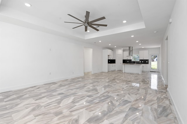 unfurnished living room with a tray ceiling and ceiling fan