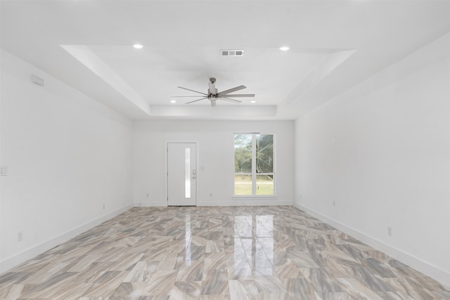 empty room with a tray ceiling and ceiling fan