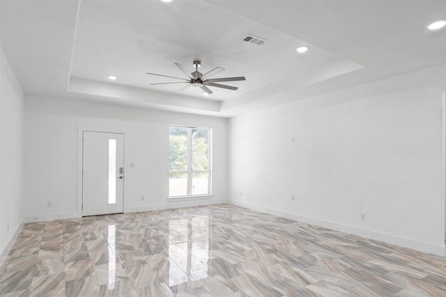 unfurnished room with a raised ceiling and ceiling fan