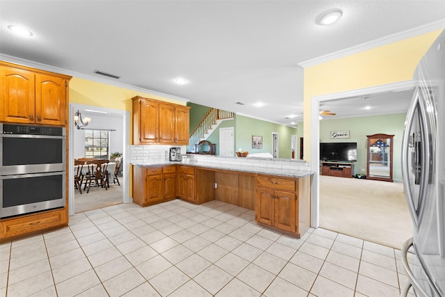 kitchen with visible vents, light carpet, appliances with stainless steel finishes, and ornamental molding