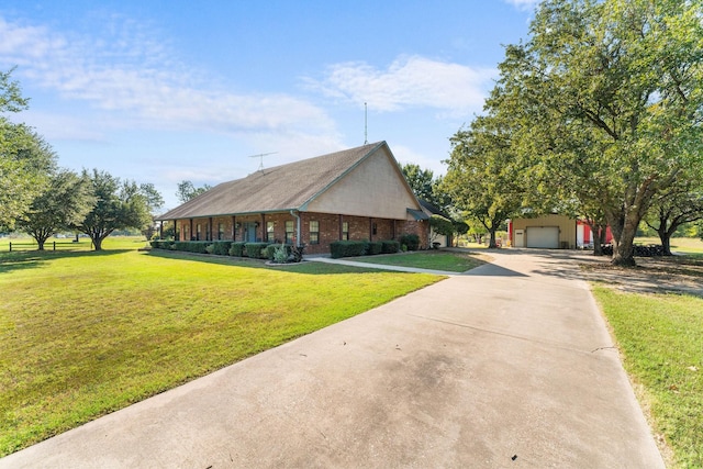 view of front facade featuring driveway, a detached garage, brick siding, and a front lawn