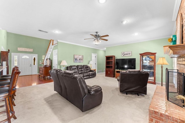 carpeted living room featuring ceiling fan, ornamental molding, and a fireplace