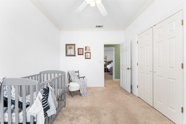 carpeted bedroom with visible vents, baseboards, a nursery area, and ornamental molding