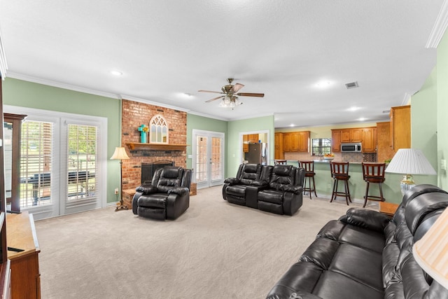 living room with a fireplace, ceiling fan, light colored carpet, and crown molding