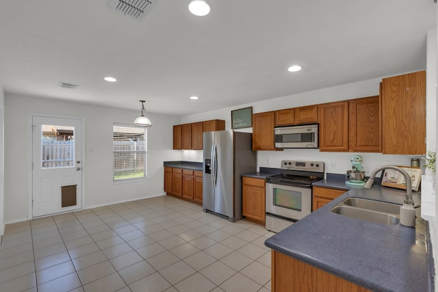 kitchen featuring light tile patterned flooring, decorative light fixtures, stainless steel appliances, and sink