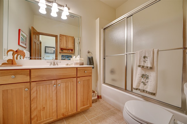 full bathroom with combined bath / shower with glass door, vanity, tile patterned floors, and toilet