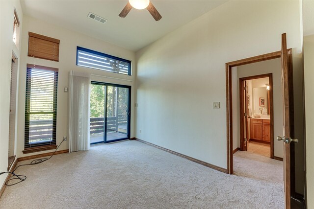 empty room featuring ceiling fan, light colored carpet, and high vaulted ceiling