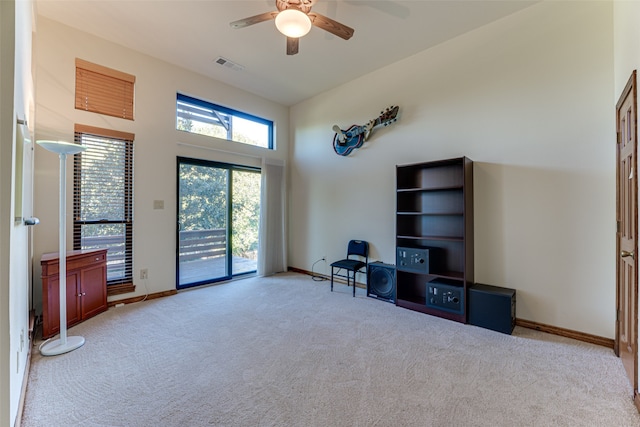 living area with light carpet, a high ceiling, and ceiling fan