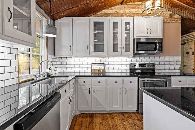 kitchen featuring stainless steel appliances, sink, white cabinets, vaulted ceiling with beams, and hanging light fixtures