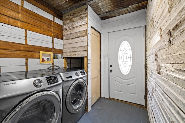 laundry area with washing machine and clothes dryer and wooden walls