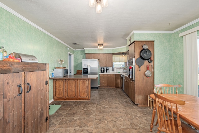 kitchen with kitchen peninsula, ornamental molding, a textured ceiling, and appliances with stainless steel finishes