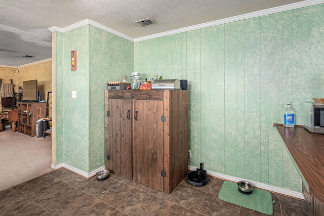 interior space with wooden walls, crown molding, and a textured ceiling