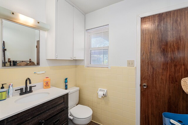 bathroom with vanity, toilet, and tile walls