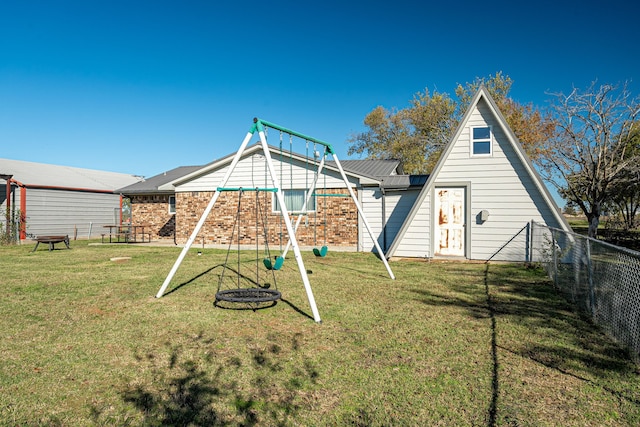 back of property featuring a playground and a lawn