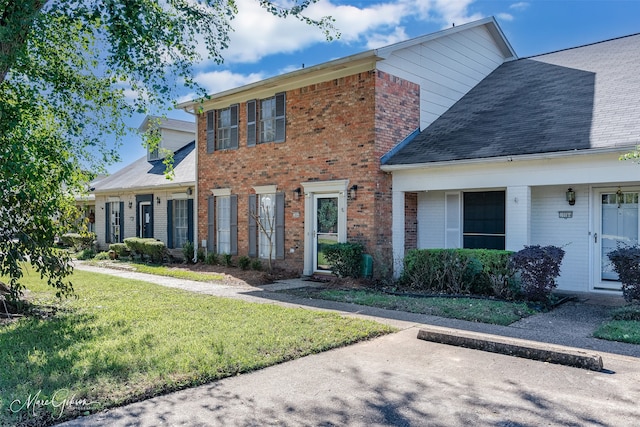 view of front facade featuring brick siding and a front yard