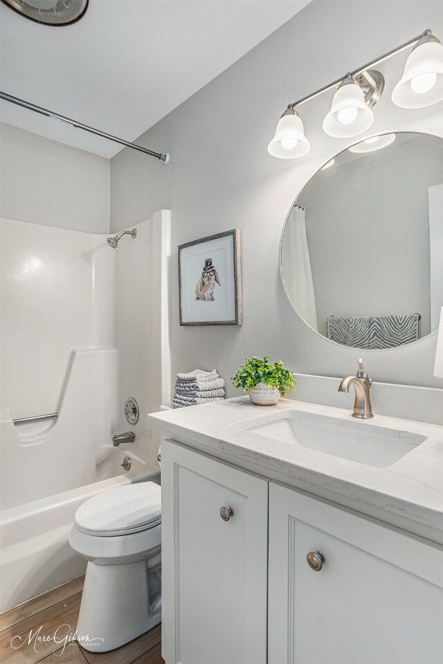 full bathroom featuring washtub / shower combination, wood-type flooring, vanity, and toilet