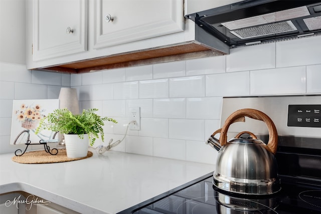 kitchen featuring white cabinets, extractor fan, and tasteful backsplash