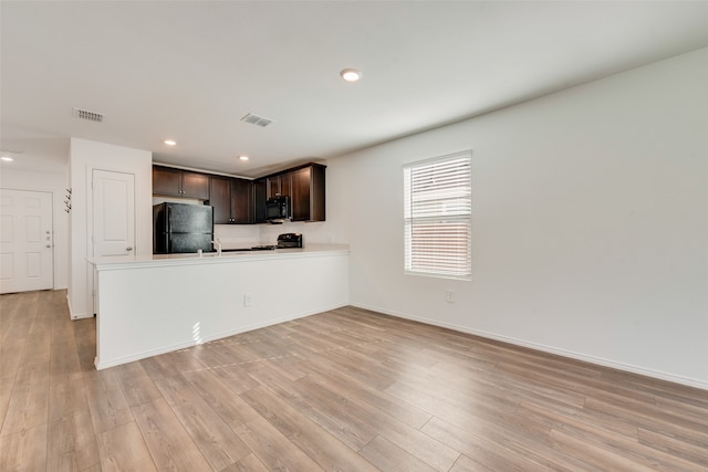 kitchen featuring sink, kitchen peninsula, light hardwood / wood-style floors, dark brown cabinets, and black appliances