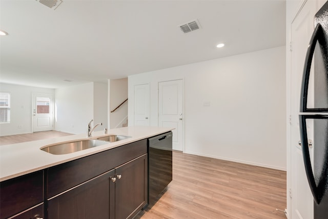 kitchen with sink, dark brown cabinets, light wood-type flooring, and black appliances