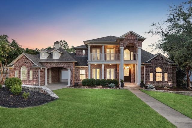 view of front of home with a balcony and a lawn