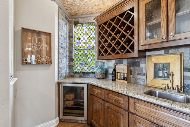 bar featuring wine cooler, light stone countertops, sink, and decorative backsplash