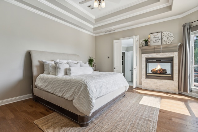 bedroom featuring hardwood / wood-style floors, ceiling fan, a multi sided fireplace, and crown molding