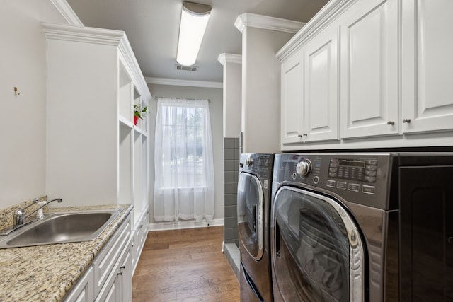 laundry area featuring cabinets, dark hardwood / wood-style flooring, ornamental molding, sink, and independent washer and dryer