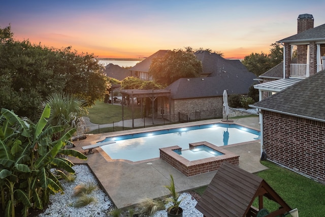 pool at dusk featuring a lawn, a diving board, a patio area, an in ground hot tub, and a water view